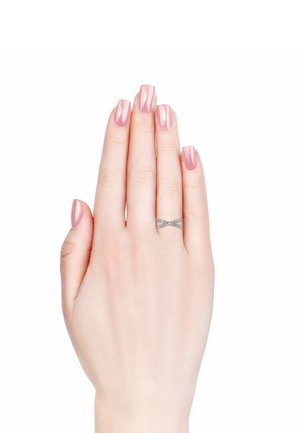 Anello d'argento con un design incrociato adornato da piccoli cristalli trasparenti, esposto su una mano con unghie rosa e lucide. Mano inclinata per una migliore visibilità.