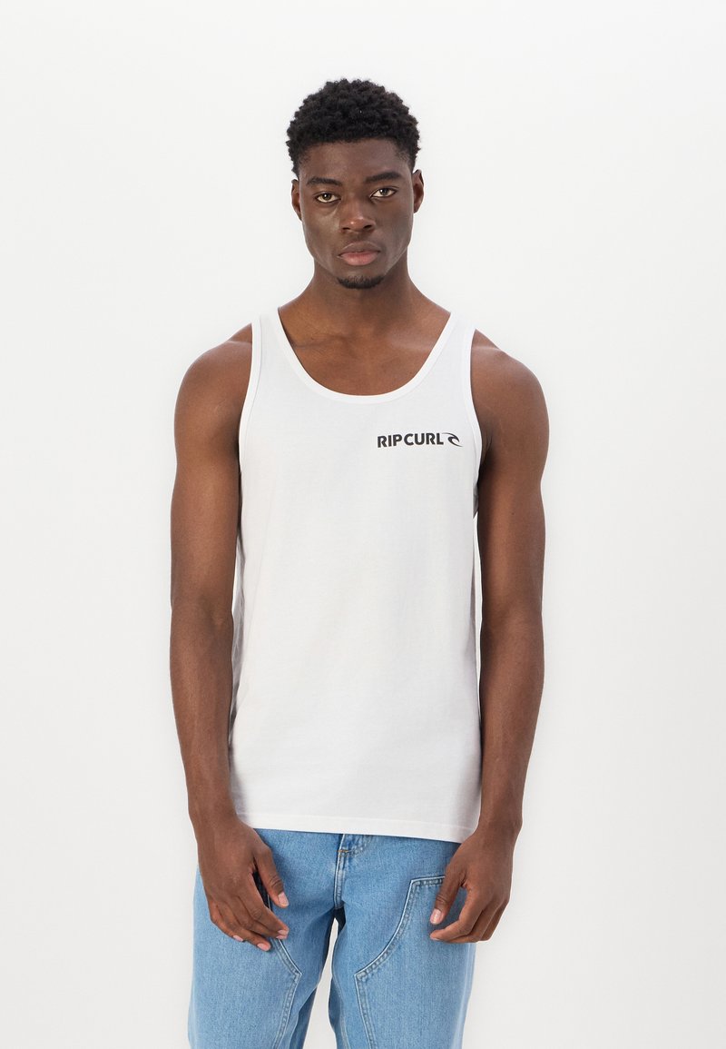 Un tricou alb din bumbac, cu guler rotund, având un logo negru "RIP CURL" pe piept, asortat cu blugi din denim de culoare albastră deschisă.