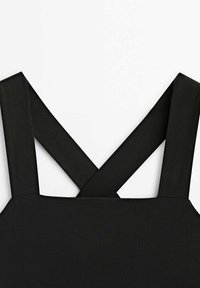 Schwarzer Stoff mit einer glatten Textur, der breite, gekreuzte Träger aufweist. Das Design betont die Schlichtheit und verleiht einen modernen Look.