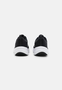 Chaussures de sport noires avec une tige en mesh, une semelle intermédiaire blanche et une semelle extérieure en caoutchouc texturé. Conçues avec une languette pour un enfilage facile.