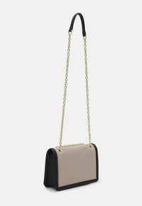 Torebka na łańcuszku o strukturalnym kształcie, z beżowym przodem i czarnymi bokami. Złote elementy ozdobne oraz gładka tekstura.