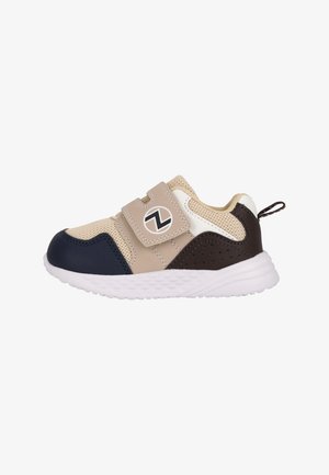 Beige og navy sneakers med mesh-overdel, velcro-rem og hvid gummisål; har sort logo og perforerede mørkebrun detaljer.