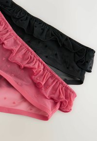 Två genomskinliga mesh-trosor, en rosa och en svart, båda med små hjärtan i mönstret och volangkant längs midjan.