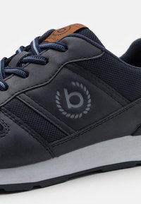 Marinblå sneakers med överdel i läder och mesh, grå logotyp och texturerade detaljer. Har blå snören och en grå gummisula.