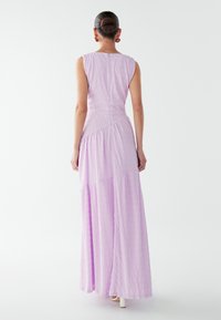 Lavender sleeveless maxi dress with textured fabric, gathered waist, and tiered skirt, featuring a keyhole back and subtle sheen.