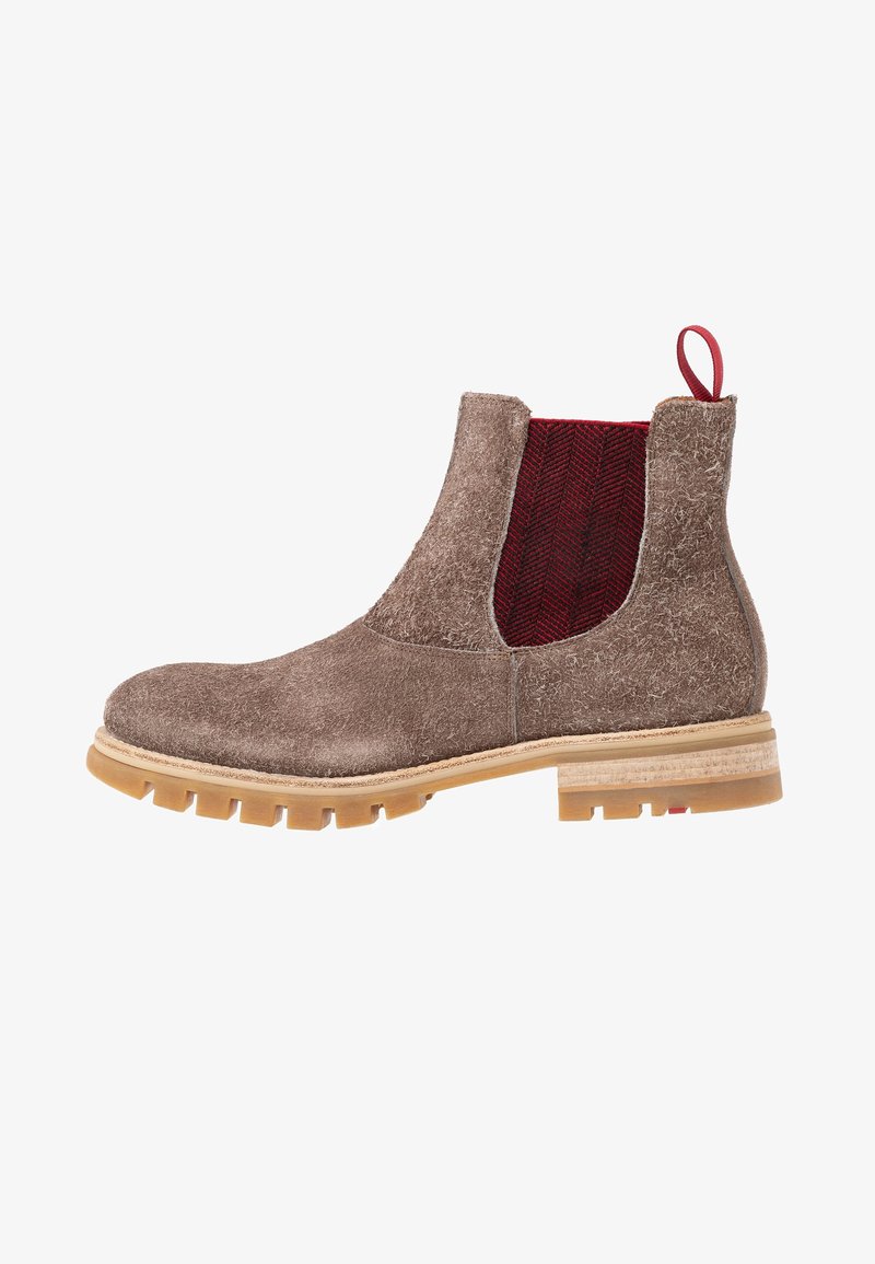 Bottine Chelsea en daim marron avec semelle beige épaisse, empiècement latéral élastique rouge et languette rouge à l'arrière.