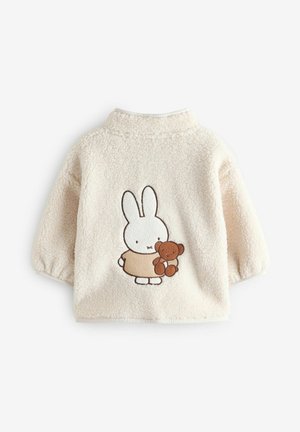 Flauschige beige Kinderjacke mit rundem Kragen und kurzen Ärmeln, verziert mit einem gestickten Design eines Kaninchens, das einen Teddybären hält.