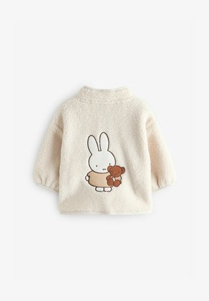 Chaqueta de niño de color beige y peluda con cuello redondo y mangas cortas, que presenta un diseño bordado de un conejo sosteniendo un oso de peluche.