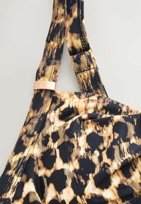 Svart och guld leopardmönstrad bygel med en mjuk textur, med en roséguld accent och sömnadsdetaljer.