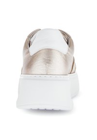 Metallisch gouden achteraanzicht van een sneaker met witte accenten en een dikke witte zool. Kenmerkt zich door een gladde textuur en heeft geen zichtbare veters.