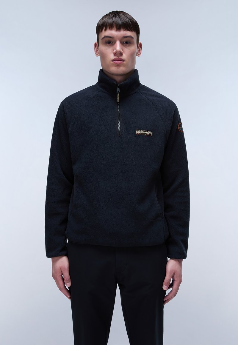 Pullover in pile nero con zip a metà, maniche raglan e una piccola etichetta con logo sul petto; texture liscia e vestibilità comoda.