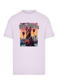 Lyslilla t-shirt med et grafisk motiv af en Dobermann med kædetrøje, sat mod en Los Angeles bylandskab og solnedgangsbagtgrund.