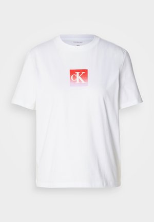 Fehér pamut póló, piros négyzet alakú logóval, rajta a "cK" fehér betűkkel. Rövid ujjú és kerek nyakkivágású. Sima textúra.