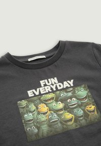 Camiseta de algodón gris oscuro con un estampado gráfico de criaturas de dibujos animados con diversas expresiones, etiquetada como "DIVERTIDO CADA DÍA".