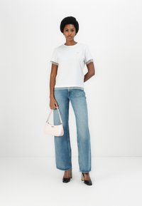 Camisa blanca con dobladillo de volante transparente, jeans de pierna ancha azul claro, bolso rosa y tacones negros. Diseño simple con un ajuste relajado.
