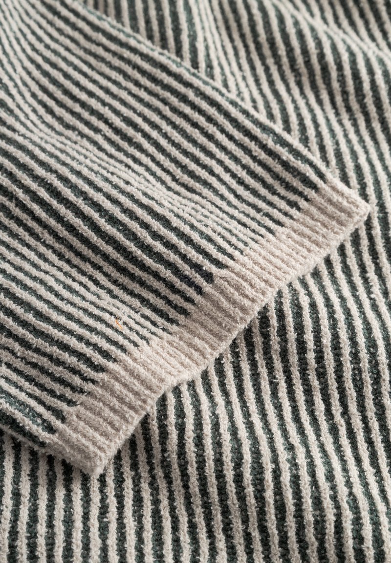 Striped fabric with alternating light beige and dark green vertical lines. Soft texture with a ribbed edge.