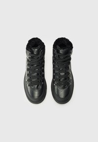 Adidași negri cu glezna înaltă, din piele texturată și căptușeală din blană artificială, având șireturile negre și ochiurile din metal.