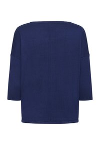 Haut bleu marine ample avec manches trois-quarts, encolure arrondie, texture côtelée et détail d'une couture centrale dans le dos.