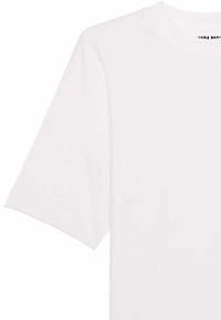 Witte katoenen t-shirt met een klassieke ronde hals en uitgesproken schouders. De stof is glad met een eenvoudig ontwerp, zonder zichtbare patronen.