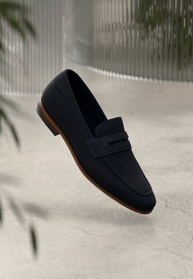 Tumed loafers sile esemelise, kootud rihma aktsendiga ja helepruuni nahksoonega. Pehme tekstuur, klassikaline kuju ja tagasihoidlik disain.