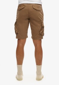 Bruine cargoshorts met vier zakken, knielang, gemaakt van katoen. Voorzien van gestikte details en een gladde textuur.