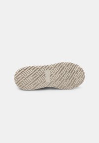 Suola di scarpa beige chiaro con un motivo geometrico testurizzato. Presenta un accento rettangolare e marchi di brand vicino al tallone.