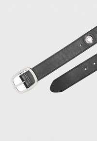 Zwarte leren riem met een rechthoekige zilveren gesp, met een gladde textuur, meerdere verstelgaten en een puntig uiteinde.