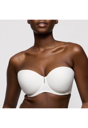 Vrouw draagt een witte strapless beha, weergegeven van schouders tot middenriff tegen een effen lichte achtergrond.