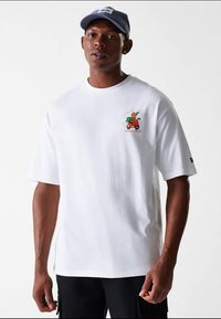 Biele bavlnené tričko s krátkymi rukávmi, na ľavej strane na hrudi farebná grafika auta s pizzou. Voľný strih, jednoduchý dizajn.