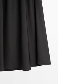 Gonna nera svasata realizzata in un tessuto leggero e liscio. Presenta un orlo che fluisce elegantemente con una leggera lucentezza e una texture morbida.