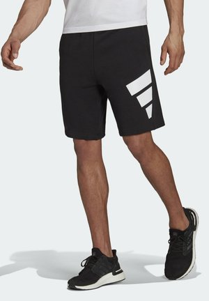 Zwarte sportbroekjes met een gladde textuur, voorzien van een grote witte diagonale streep op het linkerbeen. Elastische tailleband, kniehoogte.