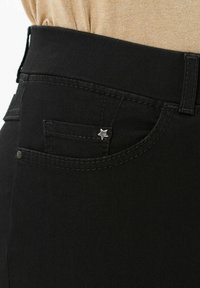 Jeans in denim nero con un accento metallico a forma di stella sulla tasca anteriore, con dettagli cuciti e una superficie liscia.