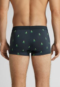 Tmavě modré boxerky z hladké látky se vzorem malých zelených vánočních stromečků se zlatými hvězdami. Elastický pas.