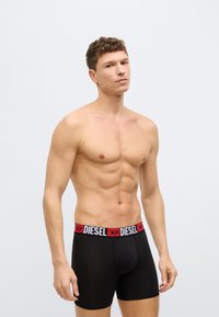 Czarne bokserki z elastycznym paskiem w talii z markowym logo w kolorach czerwonym i białym. Materiał jest gładki, a krój dopasowany.