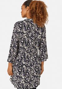 Bloemenpatroon jurk met 3/4 mouwen, getailleerde taille en een mix van paarse en zwarte kleuren op een crèmekleurige achtergrond. Gladde stofstructuur.