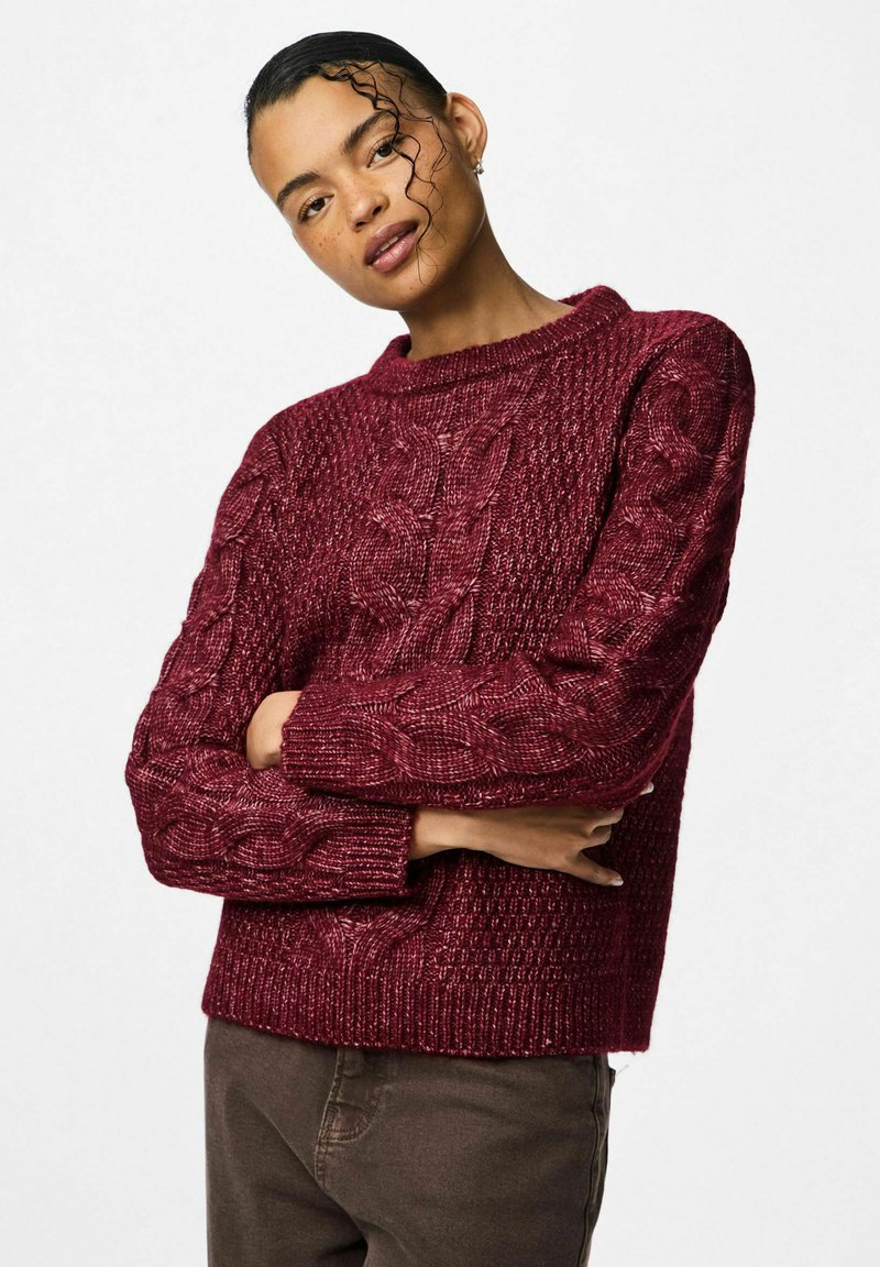 Burgundijas krāsas adīts džemperis ar ribotu tekstūru, ar apaļu kakla izgriezumu un garām piedurknēm. Piemērojumam ir brīvs un īss.