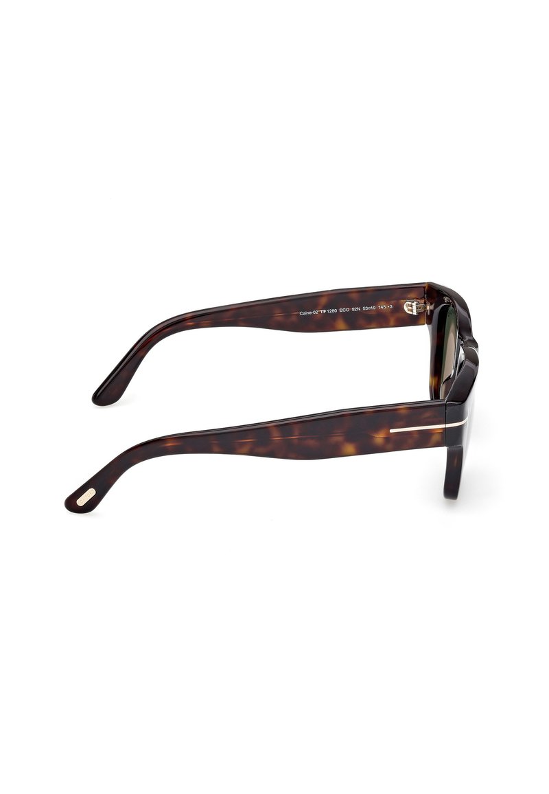 Lunettes de soleil en écaille de tortue avec des montures en plastique épaisses, des verres sombres et des branches courbées avec des accents métalliques sur les côtés.