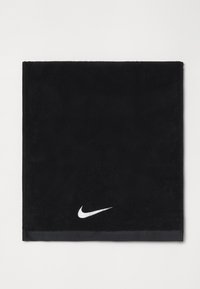 Sort bomuldshåndklæde med en blød tekstur, prydet med et hvidt Nike swoosh-logo i nederste hjørne og en kontrasterende sort kant.