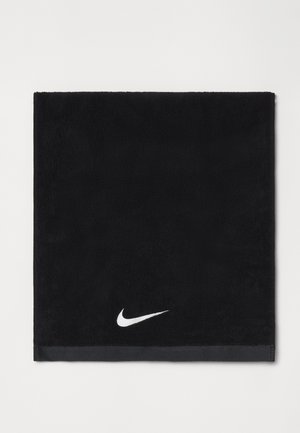 Zwarte katoenen handdoek met een zachte textuur, voorzien van een wit Nike swoosh-logo in de onderste hoek en een contrasterende zwarte rand.