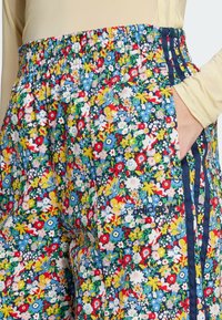 Pantaloni con stampa floreale caratterizzati da un design multicolore con tonalità di blu, rosso, giallo e verde. Vita elastica e dettagli con tasca laterale.