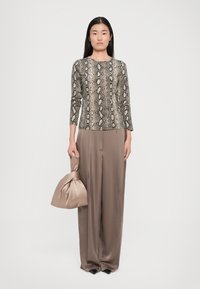 Snakeskin-patterned top with long sleeves, paired with high-waisted, beige wide-leg trousers and a taupe satin bag. Smooth texture.