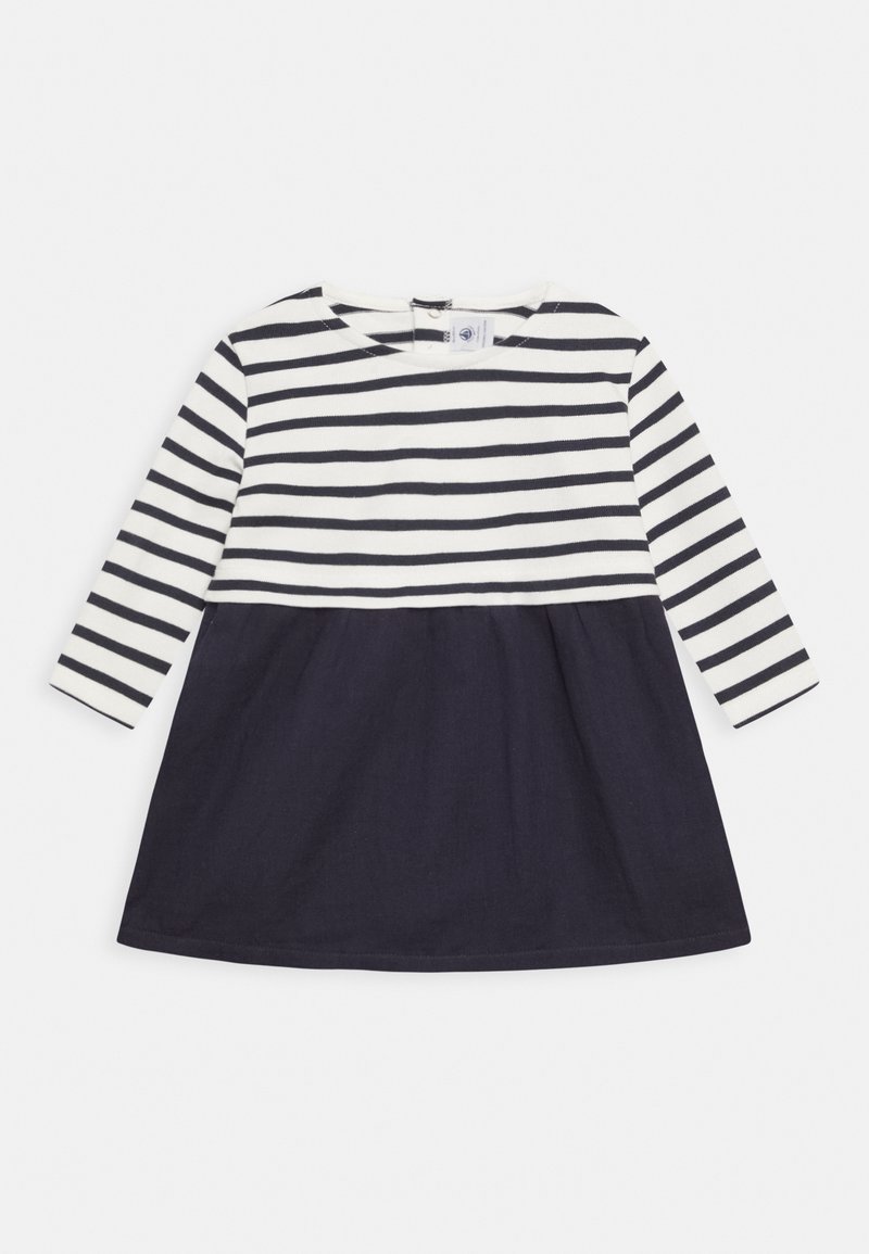Vestido de manga larga a rayas con un fondo azul marino y una parte superior blanca. La parte superior presenta rayas negras horizontales; la tela es suave y ligera.