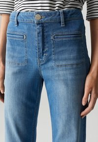 Lichtblauwe denim jeans met een hoge taille, twee voorzakken en twee achterzakken met zichtbare stiksels. Een gladde textuur en een klassieke pasvorm.