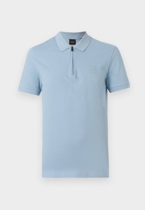 Polo à manches courtes bleu clair avec un col zippé et une petite écusson carré sur la poitrine gauche.