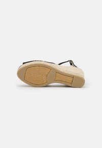 Sandalo espadrilles nero con piattaforma in iuta intrecciata e suola in gomma. Caratterizzato da una cinghia alla caviglia con hardware dorato e una soletta testurizzata.