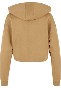 Sudadera recortada en tejido de color beige claro, presenta una capucha, mangas largas y puños de canalé; textura suave con un diseño simple y limpio.