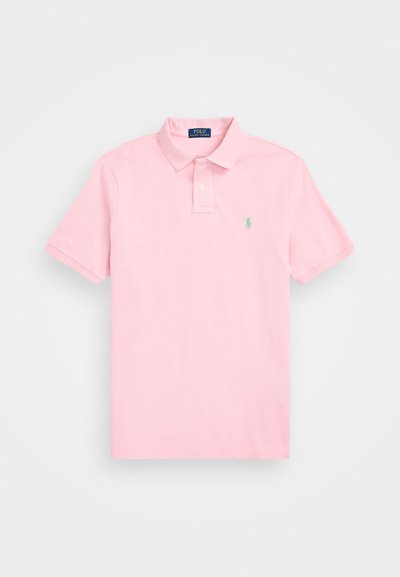 Light pink polo shirt made of cotton. Features a classic collar, short sleeves, and a small green logo on the left chest.