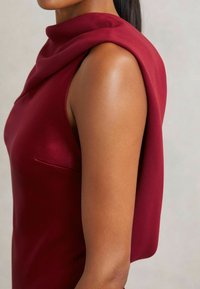 Burgunderfarbenes ärmelloses Kleid mit einem drapierten Kragen und einem glatten Satinfinish. Verfügt über eine kleine Seitentasche.