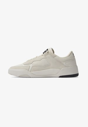 Beżowy niski sneaker z panelami z siateczki i zamszu, zawiązywany na sznurówki, z grubą podeszwą i czarnymi akcentami na pięcie i języku.