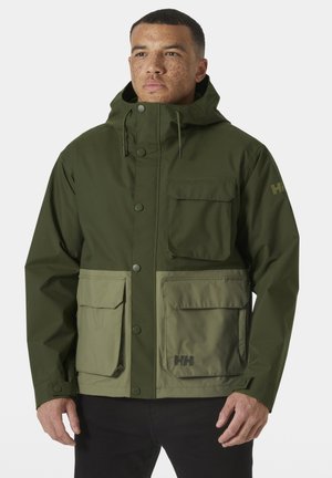 Chaqueta impermeable verde con cremallera frontal, dos grandes bolsillos frontales y capucha ajustable. Textura suave con detalle del logo en la manga.